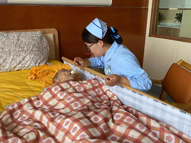 护士为行动不便的老人喂饭。青海省卫生健康委员会供图