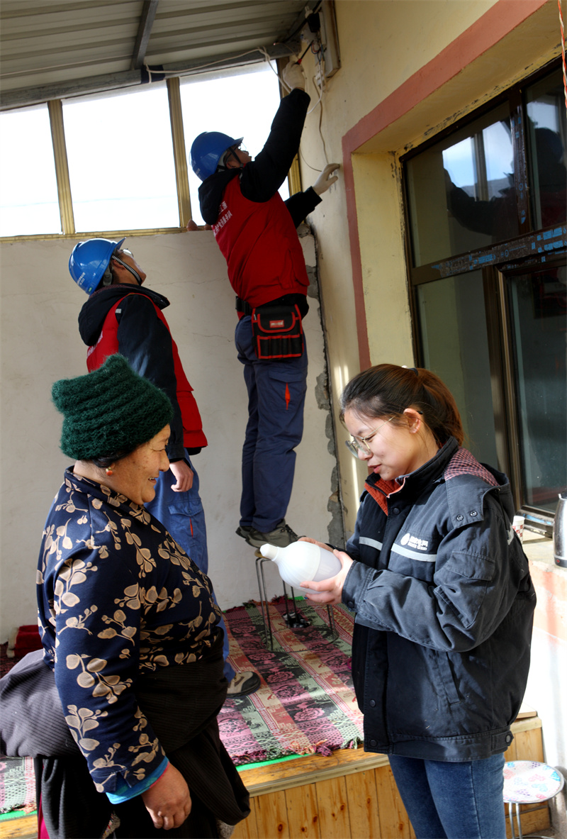 1月13日，国网青海同仁市供电公司员工为牧民群众检查用电线路并赠送节能灯泡。祁正吉摄