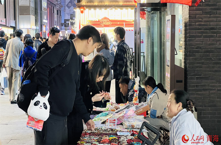 夜晚集市上摆摊的摊主和挑选商品的顾客。人民网 顾斐菲摄