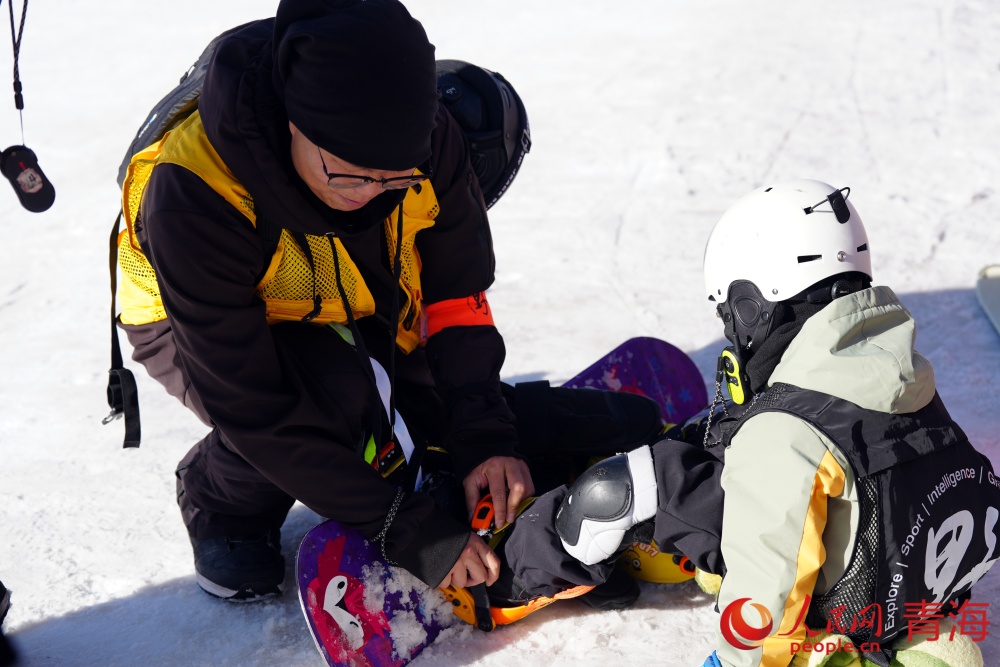 教练给同学调整雪板。实习生 葛嵘摄