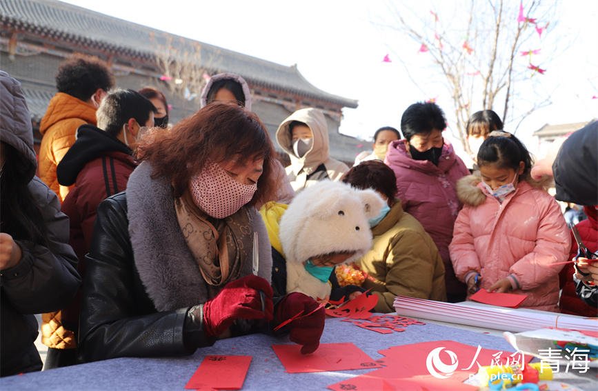 活动现场，市民游客围坐在一起剪纸。人民网 马可欣摄
