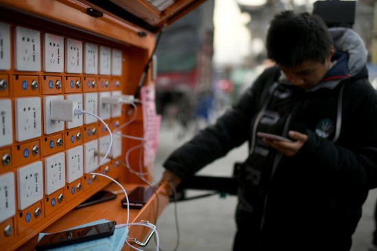 12月20日，在甘肃省临夏州积石山县大河家镇大河村集中安置点，受灾群众正在充电站给手机充电。人民网记者 翁奇羽摄
