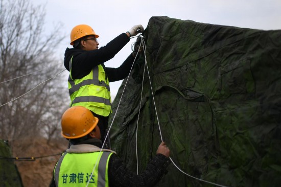 12月20日，甘肃省临夏州积石山县大河家镇大河村集中安置点，工作人员在布设无线网络。人民网记者 翁奇羽摄